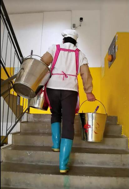 9、提着三个桶正在派送餐具的食堂阿姨.png